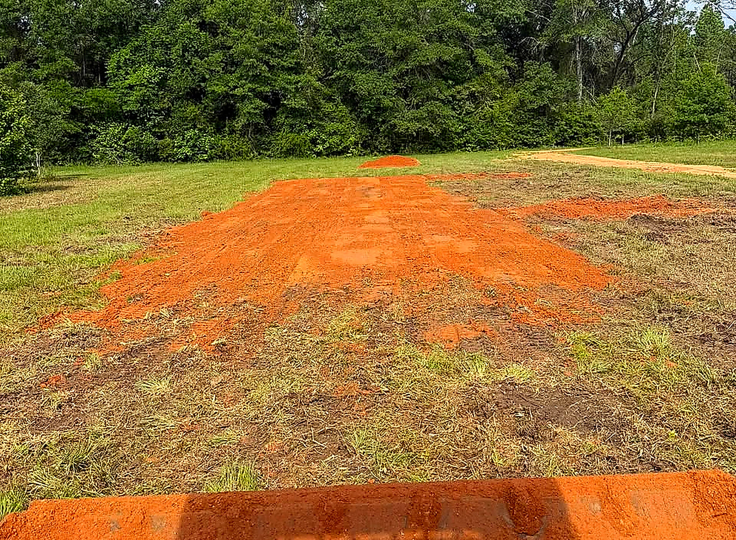 A fresh red-dirt drive laid in across a green lawn