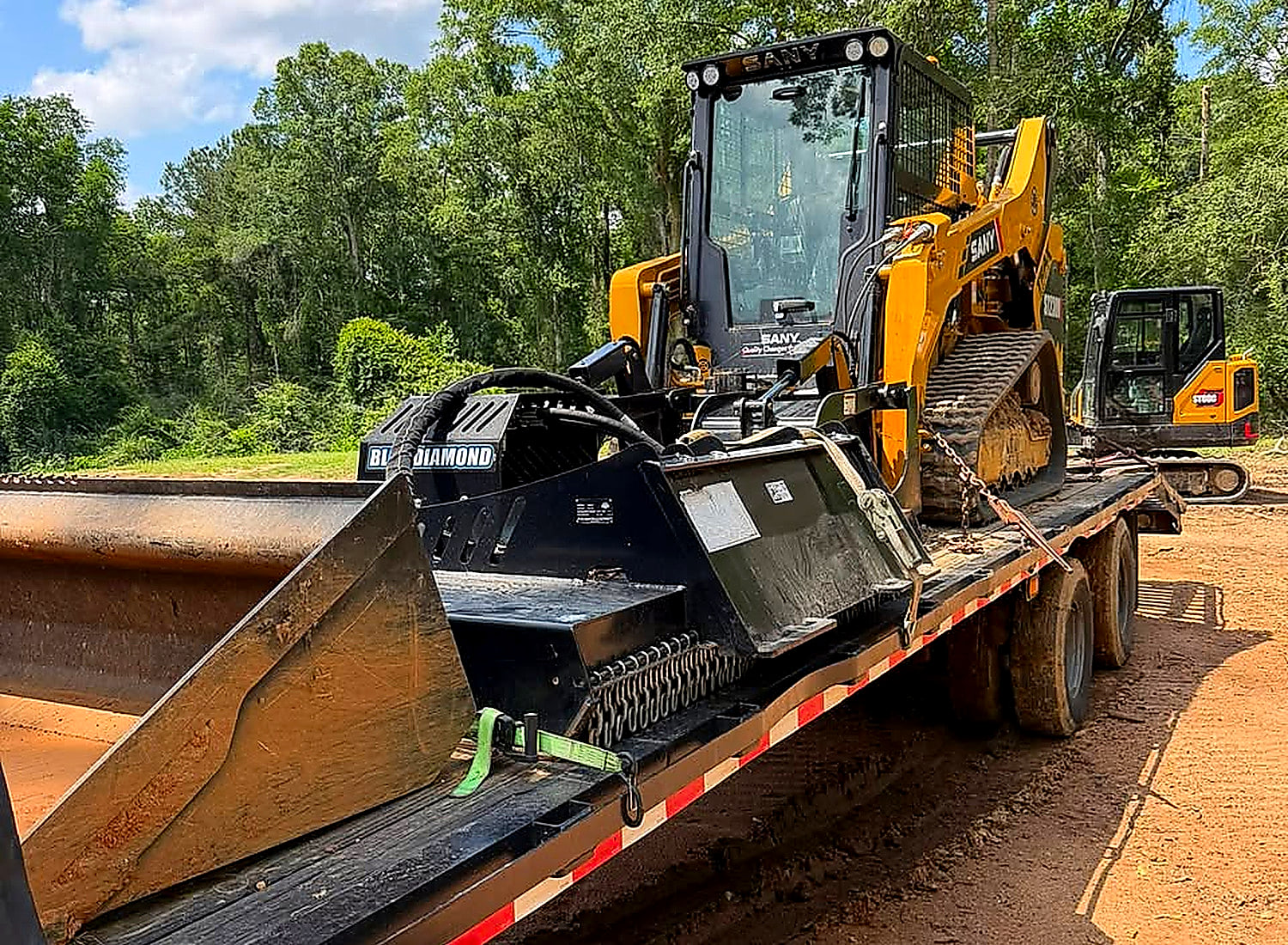 SANY track loader and excavator chained down on the lowboy trailer, loaded for the job