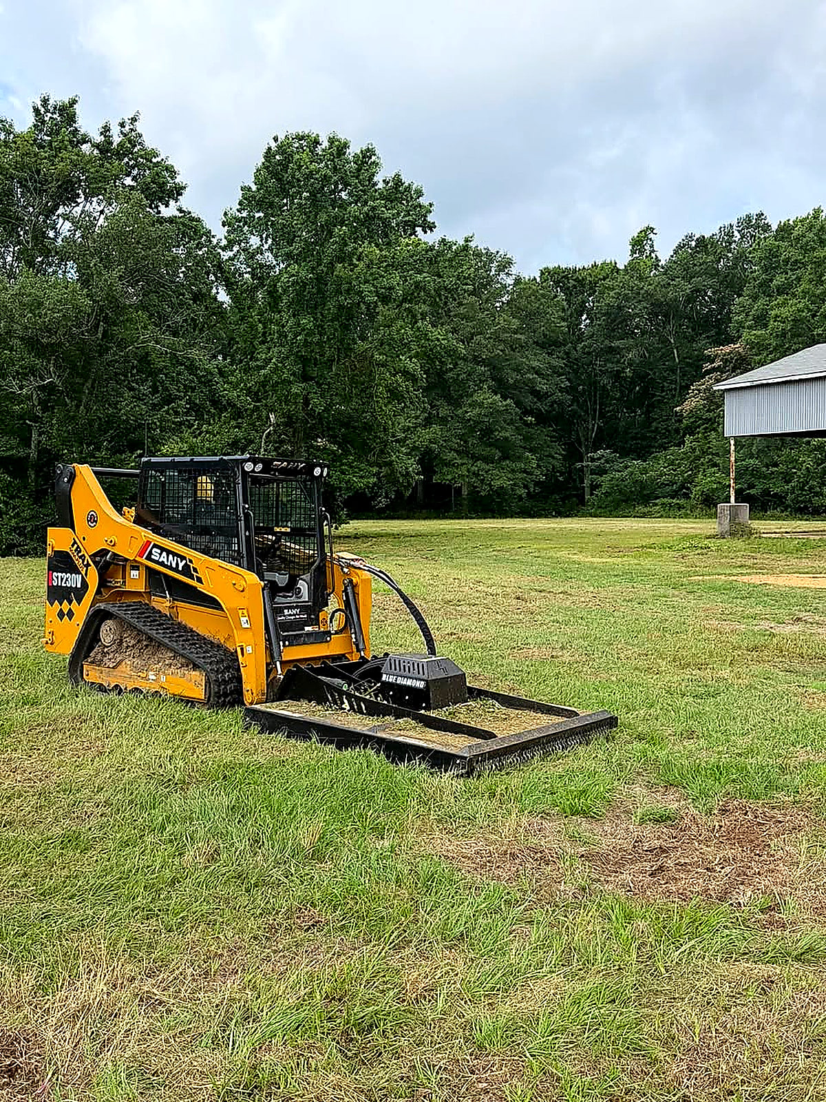 Track loader with a brush cutter attachment on a field it has just cut