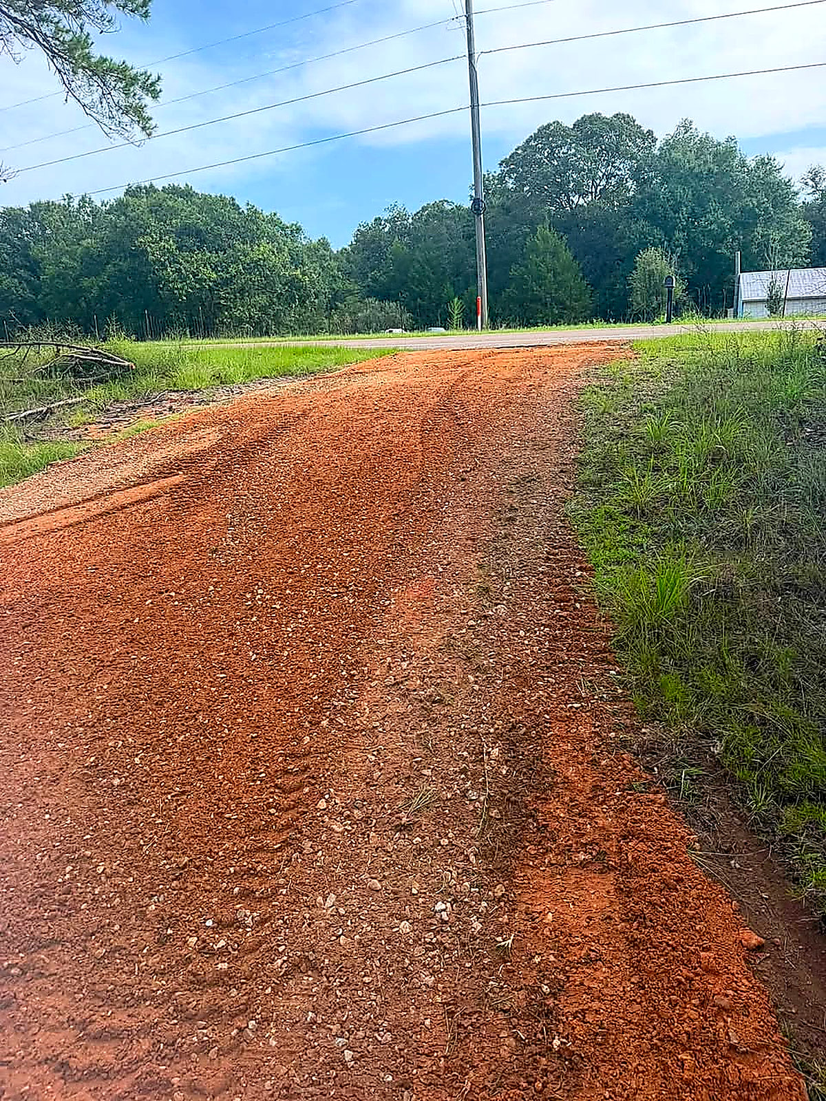 A fresh red-dirt driveway running up to the road