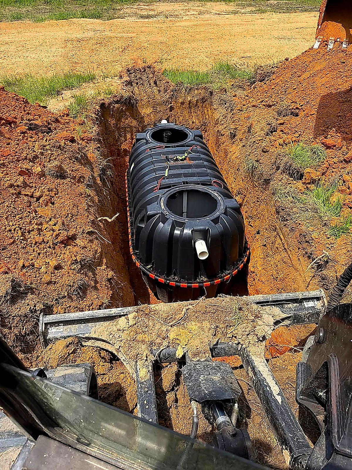 A new septic tank set down in a fresh red-clay excavation